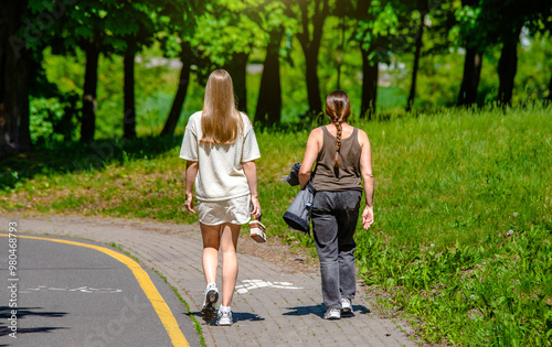 Two girlfriends walk along a path in the Park 