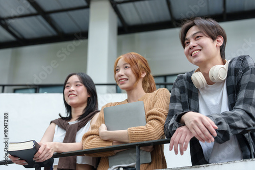 Attractive Asian college students using laptop, tablet, mobile phone to study online social media Finding knowledge together, talking, working as a team. Educational concept success in life.