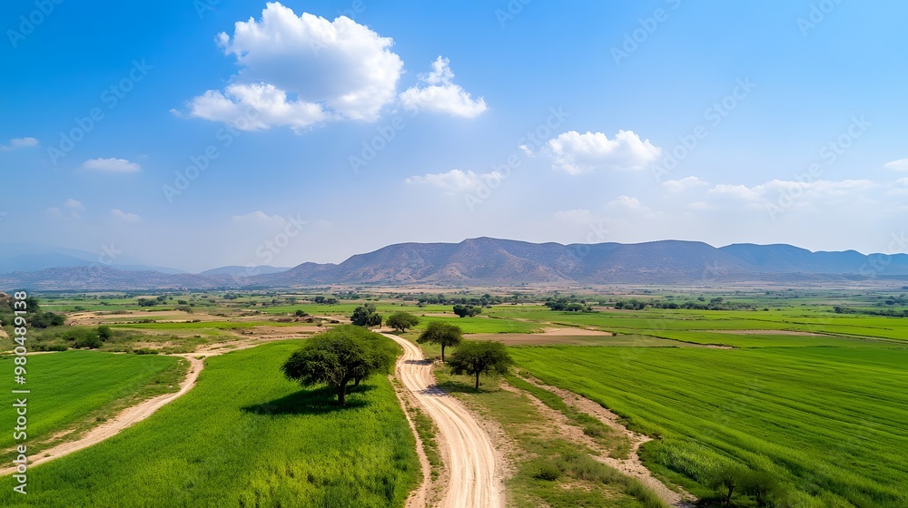 A serene landscape featuring lush green fields, winding dirt roads, and distant mountains under a bright blue sky. A serene landscape featuring lush green fields, winding dirt roads, and distant mountains under a bright blue sky.