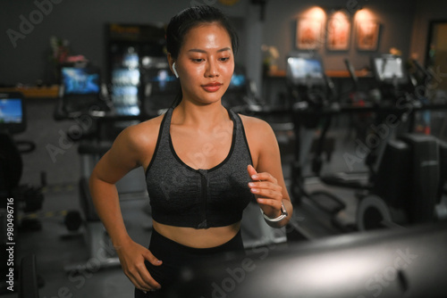 Shot of young athletic woman in sportswear running on a treadmill at gym