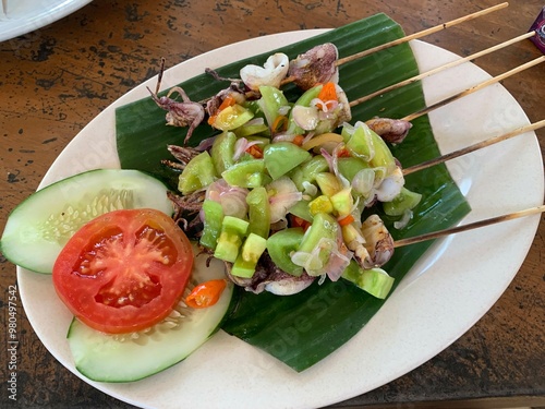 Balinese Grilled Squid with Dabu Dabu Chili Sauce. Spicy Indonesian condiment sambal made of tomato, garlic and shallot with lemon basil photo