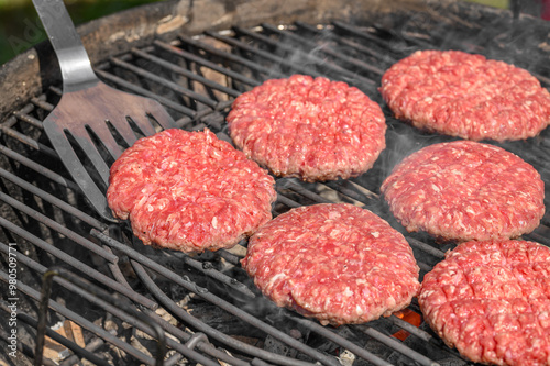Fotografie Grillmaster szykujący piękne soczyste burgery do smażenia na ruszcie