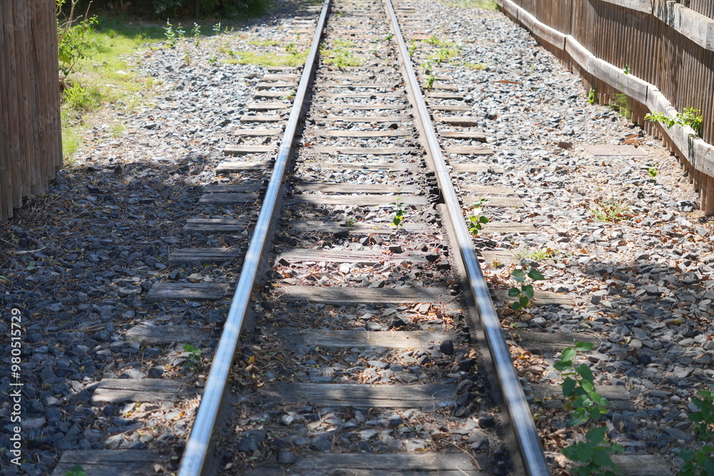The train tracks are empty and the sun is shining on them The train tracks are empty and the sun is shining on them