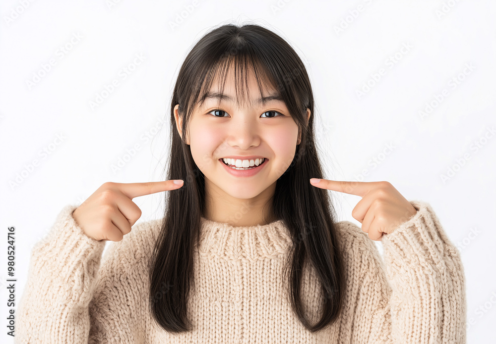 A woman with long black hair is smiling and pointing to her teeth
