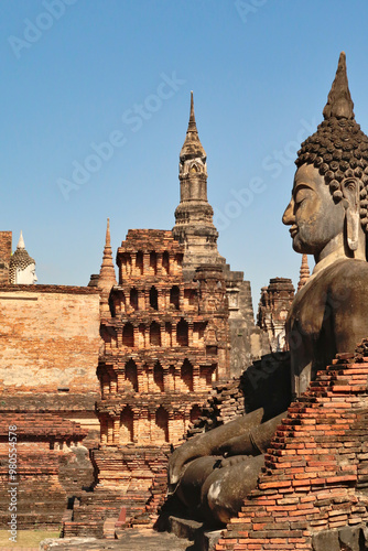 A big sitting buddha statue at the Wat Mahathat Temple with many chedis, stupas, towers in the background, Historical Park, archaeological site, ancient ruins of Sukhothai, Thailand photo