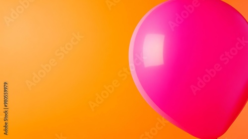 A vibrant pink balloon floats against a bright orange background, creating a cheerful and festive atmosphere. photo