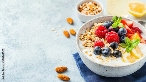 Fresh probiotic yogurt bowl topped with mixed berries, granola, almonds, and a slice of lemon on a textured blue background