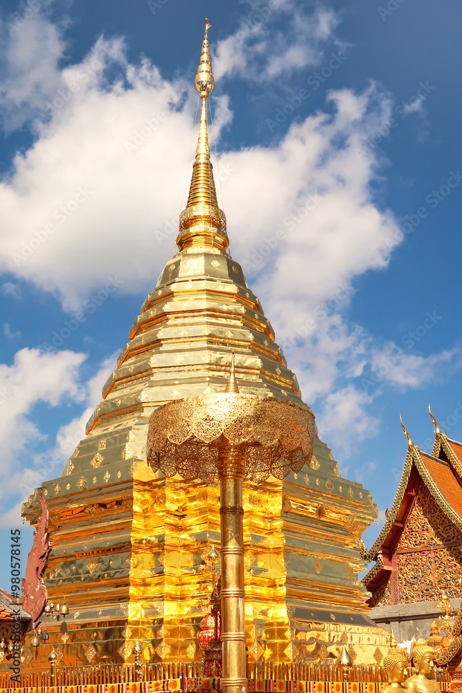 Fototapeta premium The golden central stupa, pagoda and a golden umbrella, parasol at the Wat Phra That Doi Suthep Temple, in front of a blue sky with clouds, Chiang Mai, Thailand