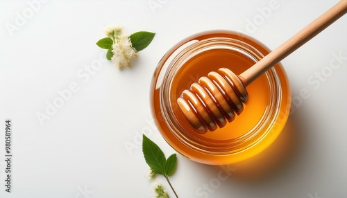 Top view of a honey jar with a wooden honey dipper on a white background with copy space