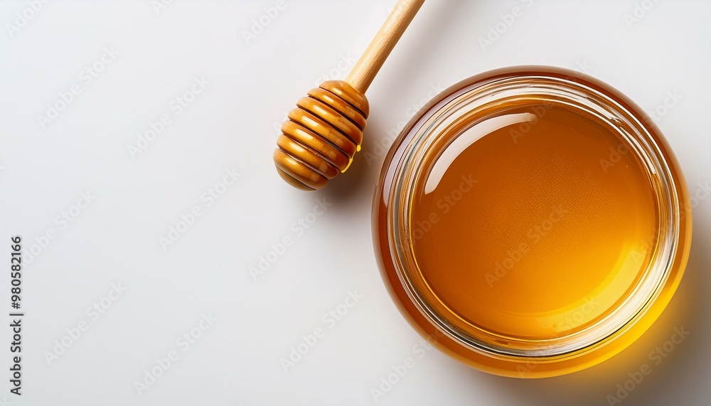 Top view of a honey jar with a wooden honey dipper on a white background with copy space Top view of a honey jar with a wooden honey dipper on a white background with copy space