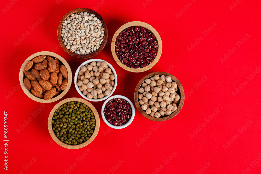 Mung beans, Red kidney beans, Chickpeas source and peeled barley in a basket wooden isolated on red background Mung beans, Red kidney beans, Chickpeas source and peeled barley in a basket wooden isolated on red background