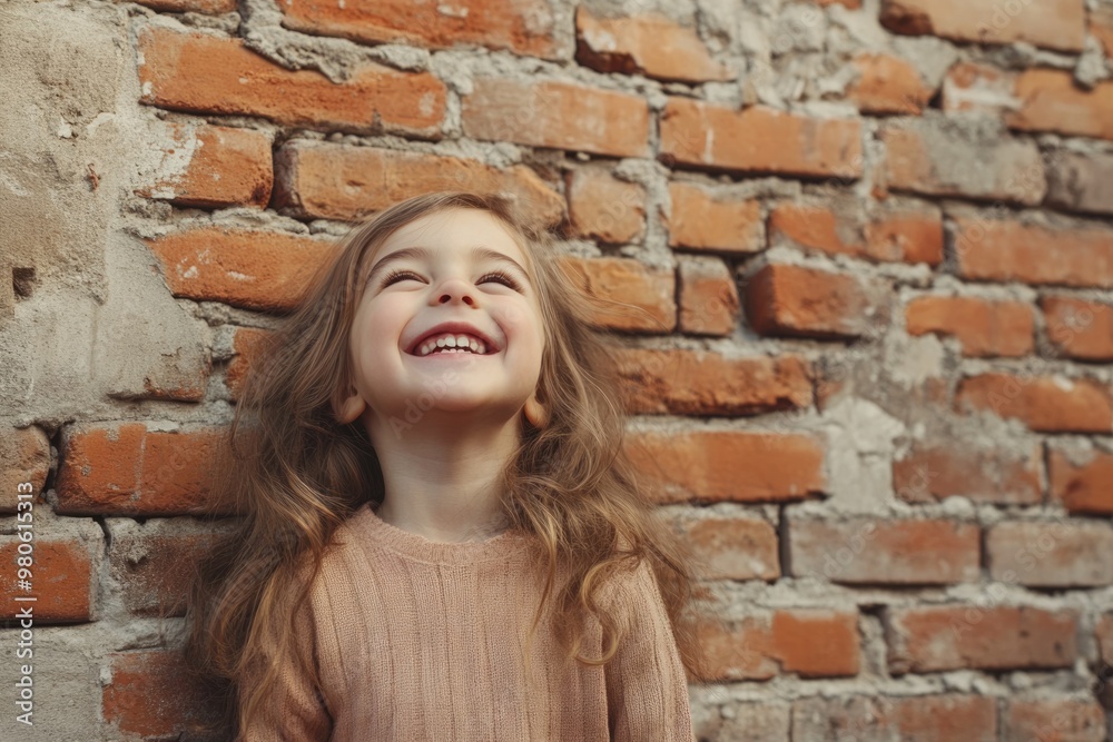 Happy child little girl laughing at a blank empty brick wall Happy child little girl laughing at a blank empty brick wall
