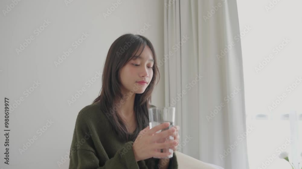 Asian young girl drinking a glass of clean water in bedroom. Teenage woman drink water after wake up in the morning for health care lifestyle and wellness in house. Asian young girl drinking a glass of clean water in bedroom. Teenage woman drink water after wake up in the morning for health care lifestyle and wellness in house.