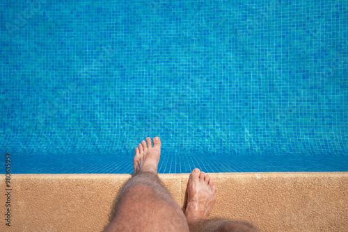 Behaarte Männerbeine Beine Füße am Schwimmbeckenrand zum Pool in blauem kleinen Mosaik photo