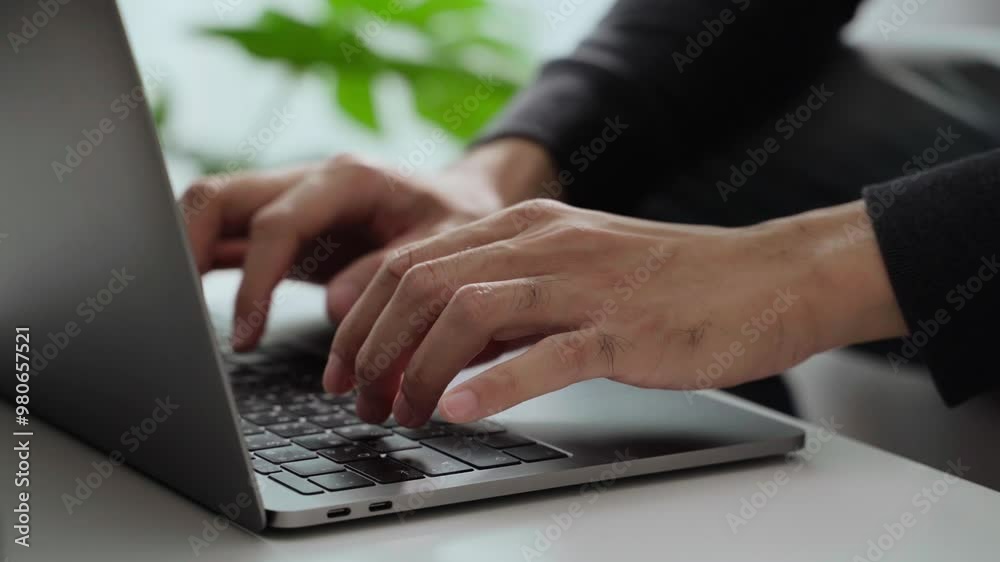 The man's hand is typing on a laptop computer keyboard at home or in the office. He is working, sending messages, chatting, browsing the internet, and using social networking.