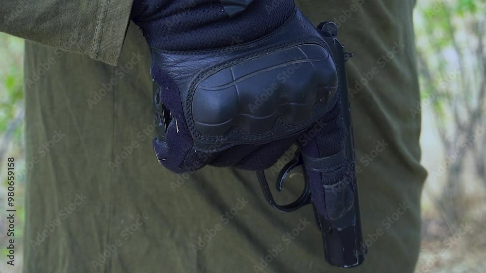 A soldier holds a loaded pistol preparing to fire. A soldier holds a loaded pistol preparing to fire.