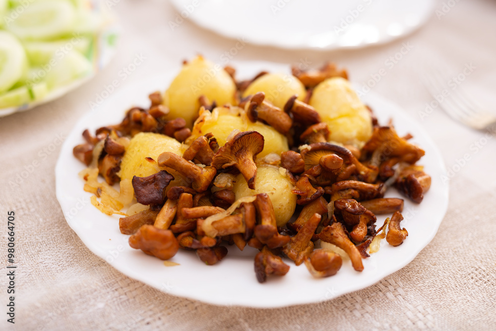 Delicious forest mushrooms chanterelles with young potatoes fried on white plate Delicious forest mushrooms chanterelles with young potatoes fried on white plate