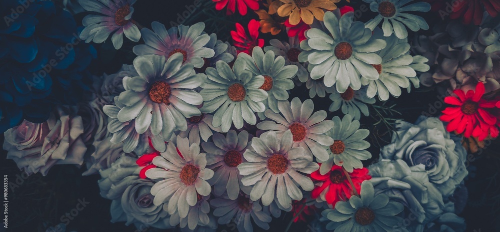 A bouquet of artificial flowers, including white daisies, pink roses, and red flowers, with vintage-style filter. A bouquet of artificial flowers, including white daisies, pink roses, and red flowers, with vintage-style filter.