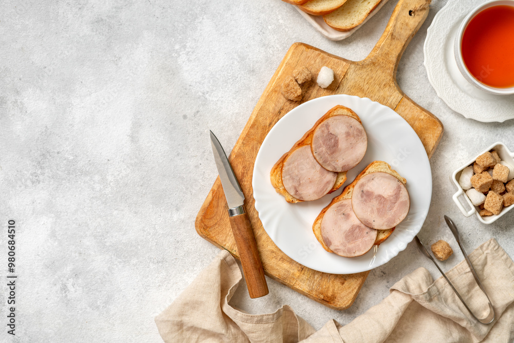 Bread with turkey ham in a white plate closeup. Toasts with sausage for breakfast on a bright table