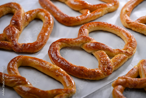 Freshly baked, golden-brown pretzels laid out on parchment paper, glistening with a slight sheen of butter. These crispy yet soft pretzels are perfect for snacking