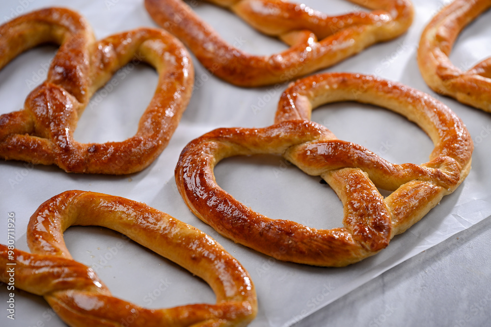 Freshly baked, golden-brown pretzels laid out on parchment paper, glistening with a slight sheen of butter. These crispy yet soft pretzels are perfect for snacking Freshly baked, golden-brown pretzels laid out on parchment paper, glistening with a slight sheen of butter. These crispy yet soft pretzels are perfect for snacking
