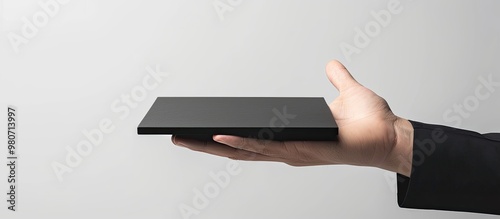 A versatile office icon on a sleek black pad against a pristine white backdrop showcased by a businessman s hand conveys the adaptable office concept with ample copy space image photo