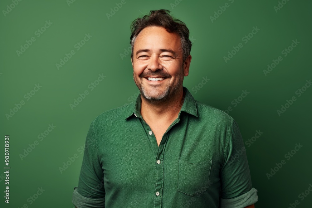 Fototapeta premium Portrait of a grinning man in his 40s wearing a comfy flannel shirt in soft green background