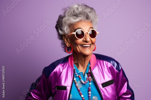 Portrait of a blissful indian woman in her 80s sporting a stylish varsity jacket in front of soft purple background photo