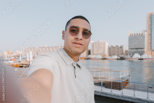 UGC portrait of an young arab male standing near waterfront. Solo traveler taking a selfie photo. Generation Z concept