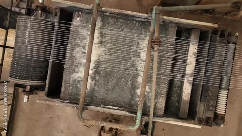 steel wire making process in factory.industrial grade heavy duty metal rope manufacturing plant. wires are going through water flow. old machinery working.