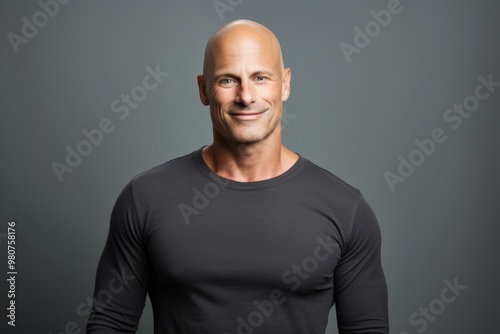 Portrait of a grinning man in his 40s sporting a long-sleeved thermal undershirt isolated in soft gray background