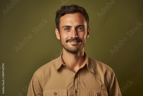 Portrait of a glad man in his 30s sporting a breathable hiking shirt isolated in soft brown background