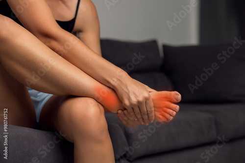 Foot pain concept, woman massaging sore feet area of heel. Discomfort painful feet ache from walking for long. The foot highlighting in red. Physical injury.
