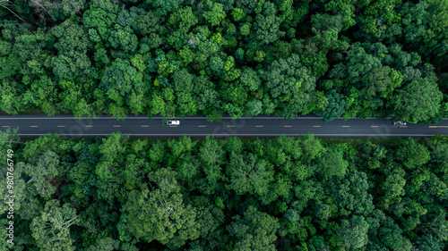 Aerial view car drive in green tree forest road winding road through the forest, Car drive on asphalt road between green tree forest, Electric vehicle EV car drive on asphalt road green tree forest.