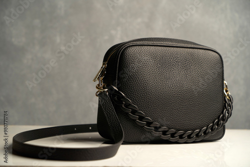 Stylish women's bag on gray background. Black leather handbag, close-up