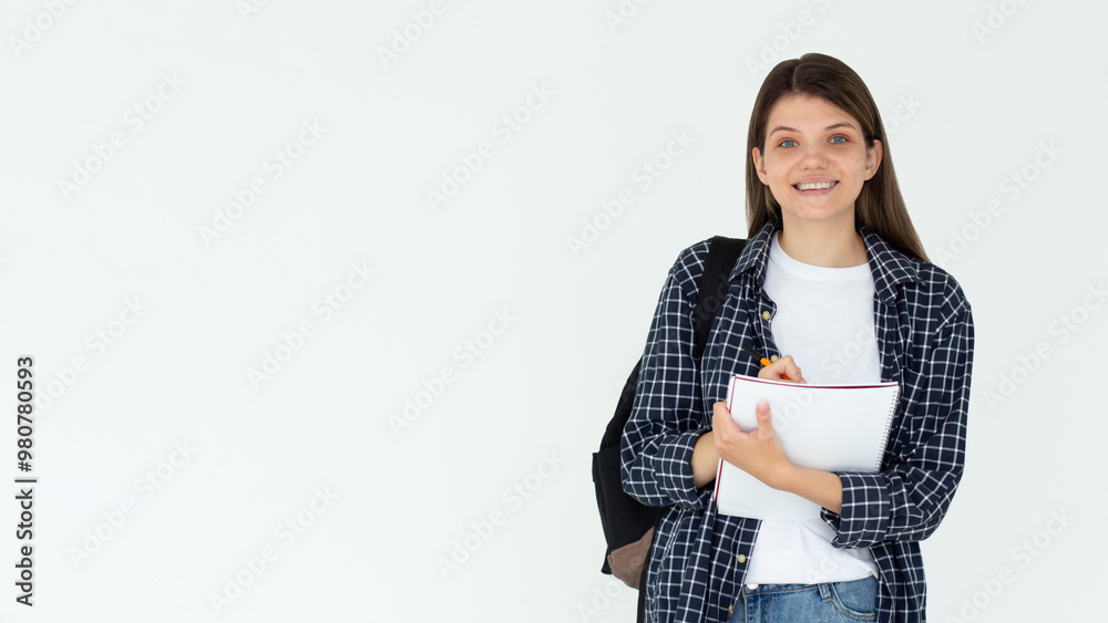 Happy teen student girl wears blue shirt backpack hold book write down lesson in exercise book isolated on white background Education in university college concept Happy teen student girl wears blue shirt backpack hold book write down lesson in exercise book isolated on white background Education in university college concept