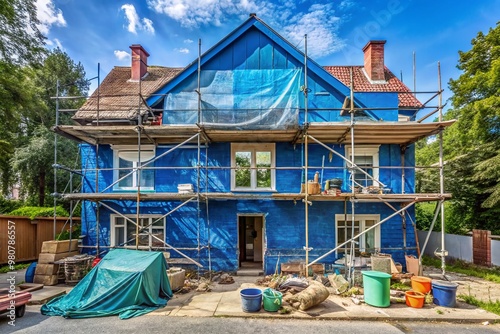 A partially renovated blue house with scaffolding and tarps exterior, amidst renovation chaos, showcasing