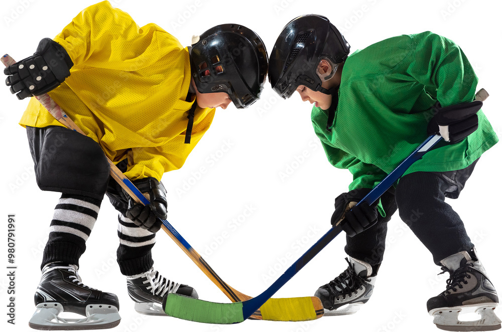 Fototapeta premium Two young hockey players, boys one in yellow and green uniform, face off with sticks hover near puck, ready for action isolated on transparent background. Concept of sport, childhood, active lifestyle