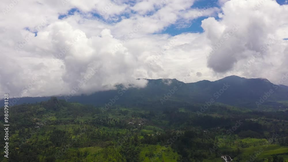 Aerial view of valley in the mountains with agricultural lands and villages against a background of blue sky and clouds. Sri Lanka. Aerial view of valley in the mountains with agricultural lands and villages against a background of blue sky and clouds. Sri Lanka.