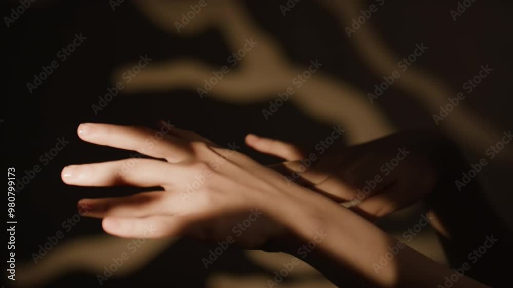 Close-up shot of female hands softly moving in semi-darkness, blurry background with decorative branches Close-up shot of female hands softly moving in semi-darkness, blurry background with decorative branches