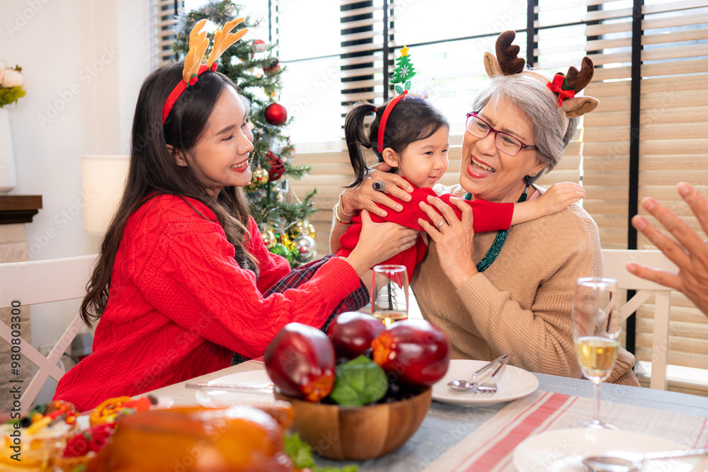 A little granddaughter lovingly hugs her grandmother, while they eating a meal together during the Christmas celebration at home A little granddaughter lovingly hugs her grandmother, while they eating a meal together during the Christmas celebration at home