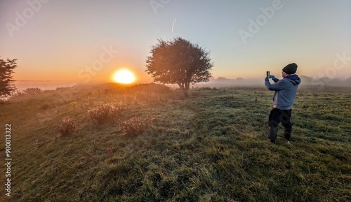 Obraz na płótnie Beautiful sunrise landscape scenery, person in the field taking photo of lonely tree, nature background, Galway, Ireland w salonie