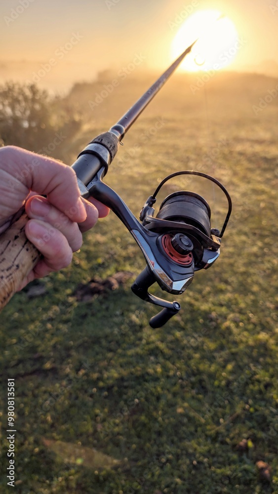 Hand holding fishing rod and reel, sunrise fishing at Clare river at Galway, Ireland, spinning, angling, catch and release, sport and leisure, nature background