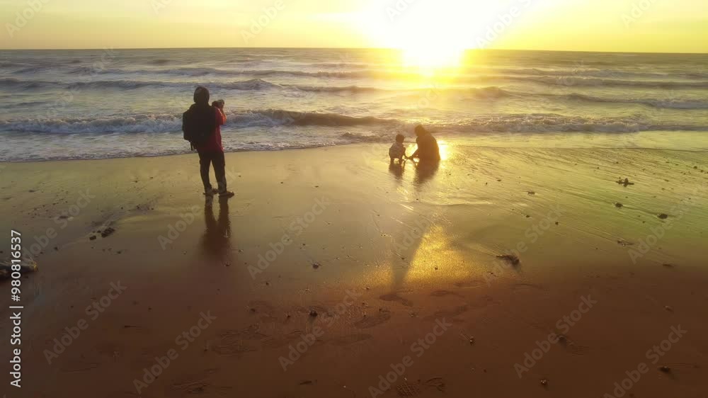 Photographer taking photos of her children during golden sunsets by the beach in slow motion. Photographer taking photos of her children during golden sunsets by the beach in slow motion.