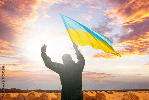 Incredibly beautiful picture as a symbol of freedom and independence of Ukraine. A soldier with a waving flag in a field in the rays of the sun