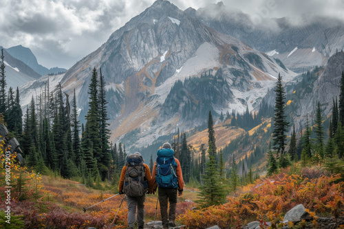 Hikers Exploring Scenic Mountain Valley in Autumn with Snowy Peaks and Evergreens