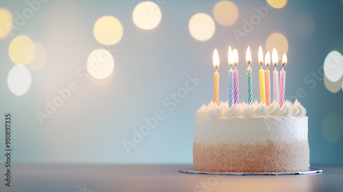 A beautifully decorated birthday cake with colorful candles glowing brightly, set against a backdrop of soft bokeh lights. The warm, festive atmosphere creates a sense of celebrati photo