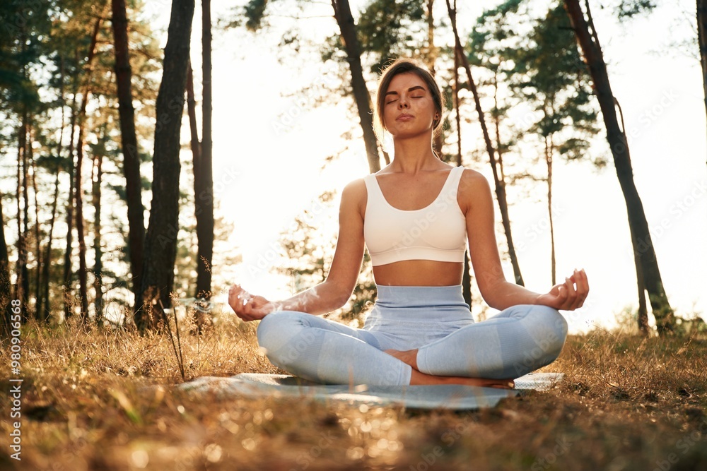 Peace and quiet, sitting. Woman is doing yoga fitness exercises in the forest Peace and quiet, sitting. Woman is doing yoga fitness exercises in the forest