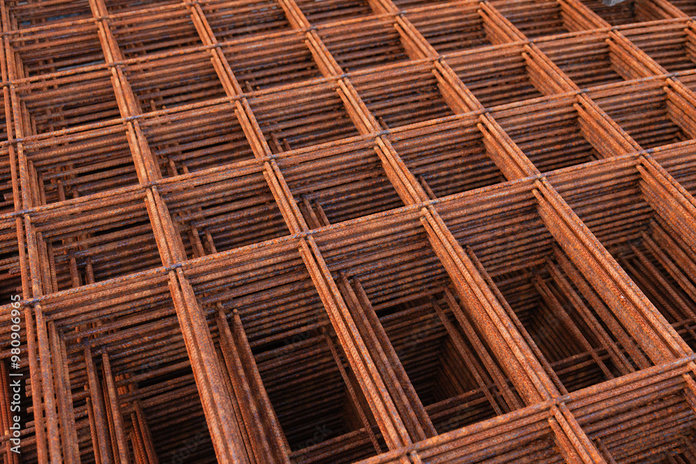 Welded, rusty, steel reinforcement is laid one on top of the other.