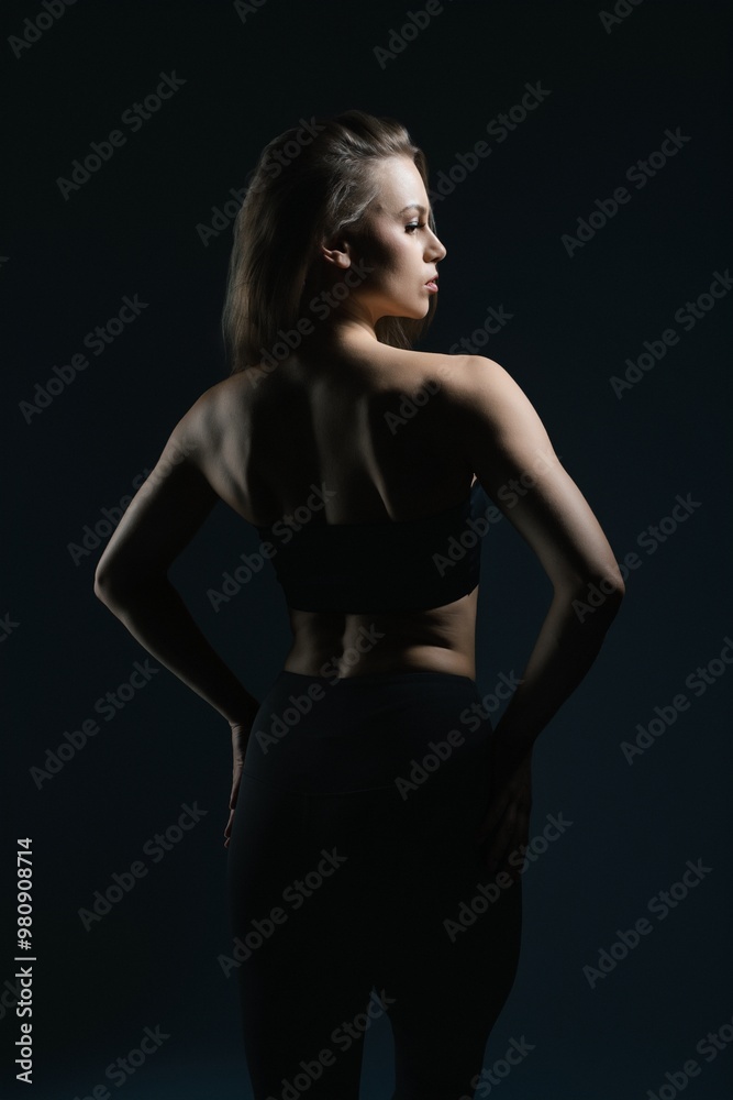 Fototapeta premium Elegant silhouette of a woman posing confidently in low light